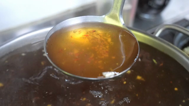 A ladle stirring a pot of broth
