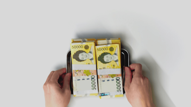 Hand taking a tray with a Korean currency on it
