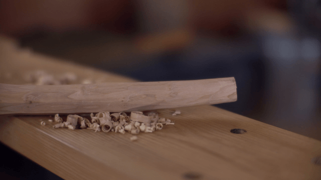 Wooden stick with wood shavings on a table