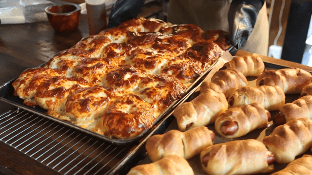 Baker taking freshly baked quattro cheese bagel out of the oven