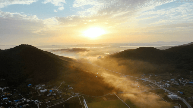 Sunrise over misty mountains and village