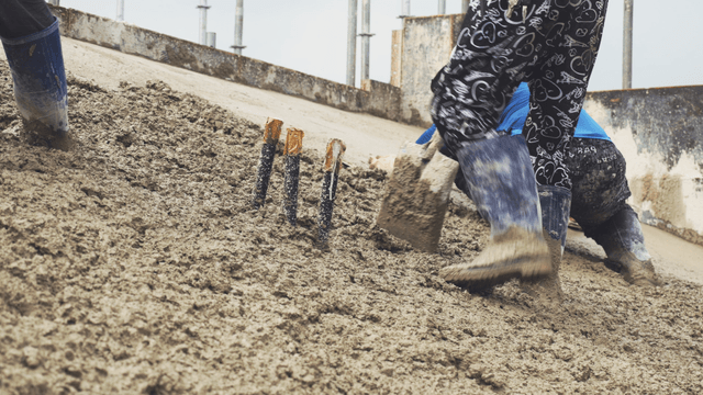 Workers smoothing wet concrete on a slope