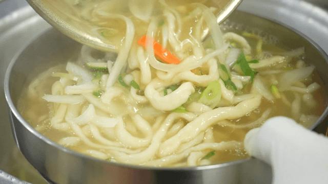 Transferring noodle soup into a bowl