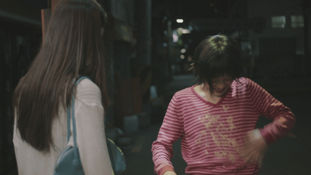 Woman smiling and brushing off while standing up with a friend watching