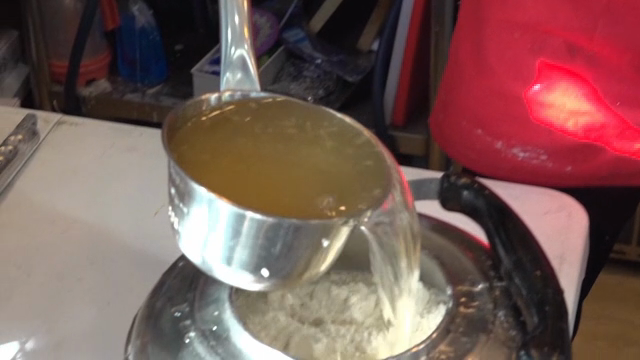 Pouring broth into a pot with flour