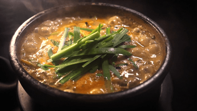 Steaming loach soup garnished with chives