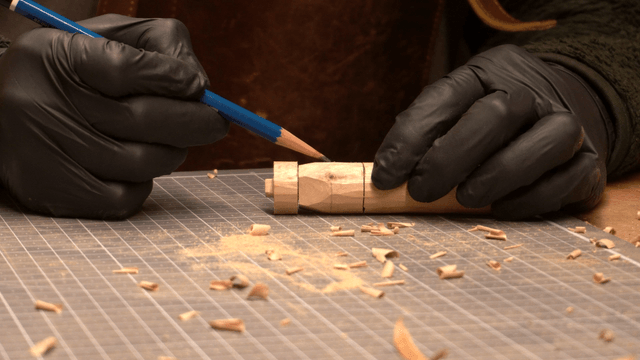 Artisan marking precisely on a wooden piece with a pencil