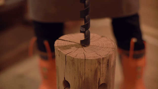 Drilling into a wooden log indoors