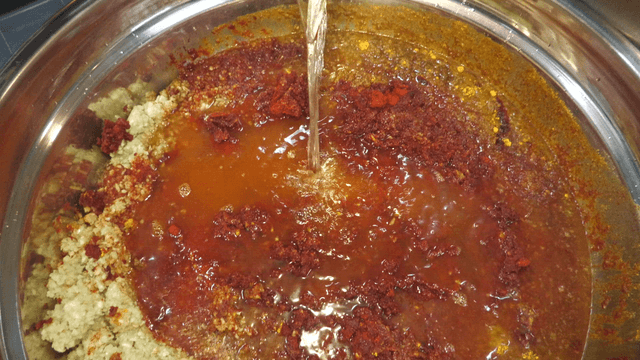 Water being poured into a bowl filled with various seasonings