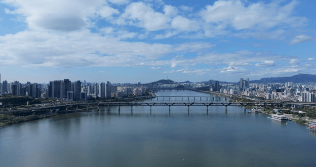 Wide river flowing under bridge connecting modern city