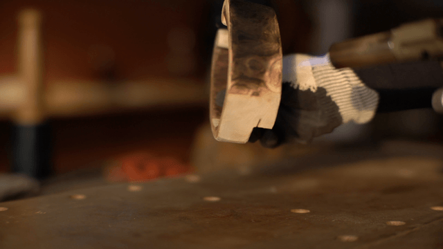 Artisan burning patterns on wood piece with torch