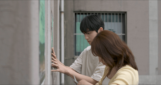 Two people posting poster on wall