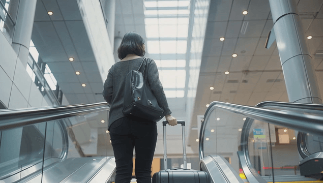 A woman with luggage on an escalator