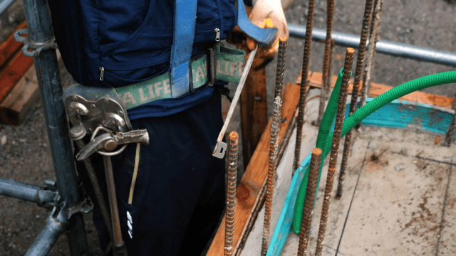 Worker measuring rebar at a construction site