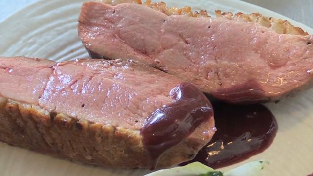 A scene of pouring sauce on plated duck meat