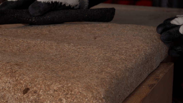 Gloved hands sanding the surface of a delicate cork sculpture