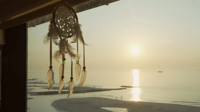 Dreamcatcher hanging by a window at sunrise