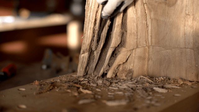 Woodcraft artisan carving grooves in a log with an awl