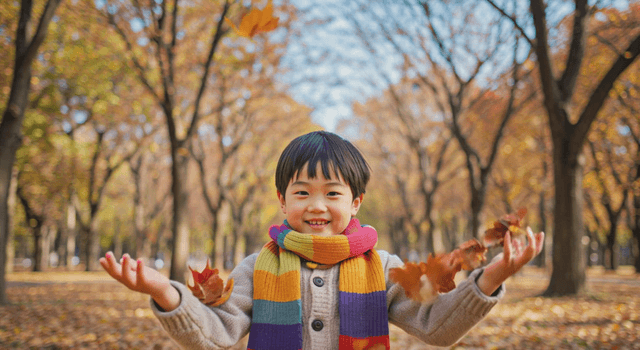 Boy playing with autumn leaves in a park