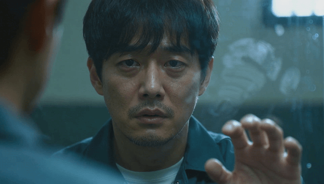 Sad male prisoner touching visitation room divider while facing forward