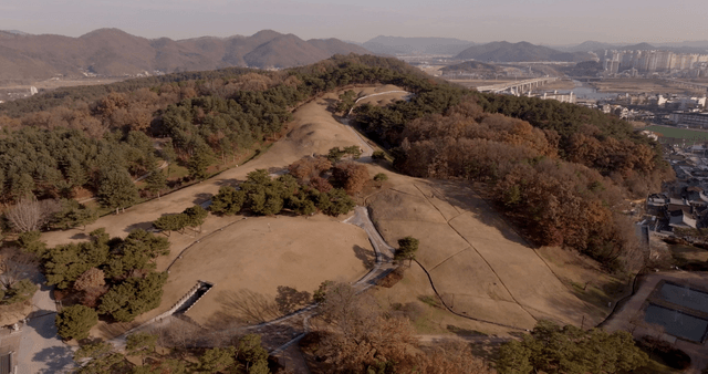 Aerial view of a forested ancient tomb and cityscape