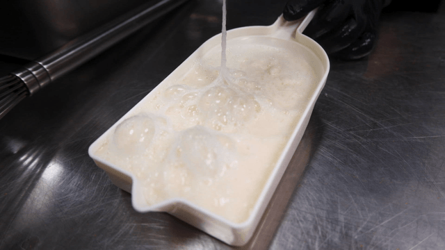Grater holding thick grated yam on kitchen counter