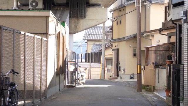 A pink train passing through a quiet alley