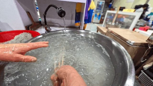 Ice fish lifted with chopsticks in kitchen