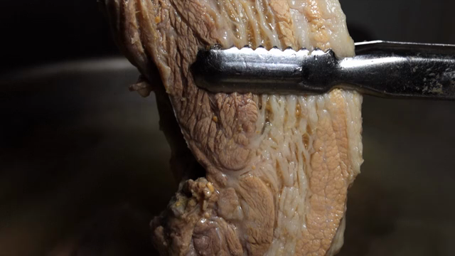 Boiled pork belly held with tongs