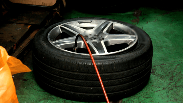 Car tire being inflated in a workshop