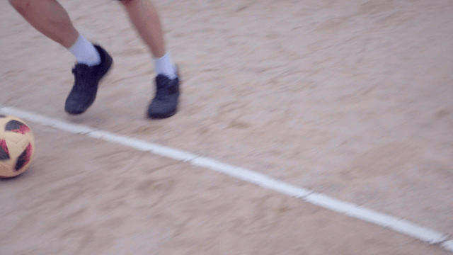 모래 운동장에서 축구를 하는 사람