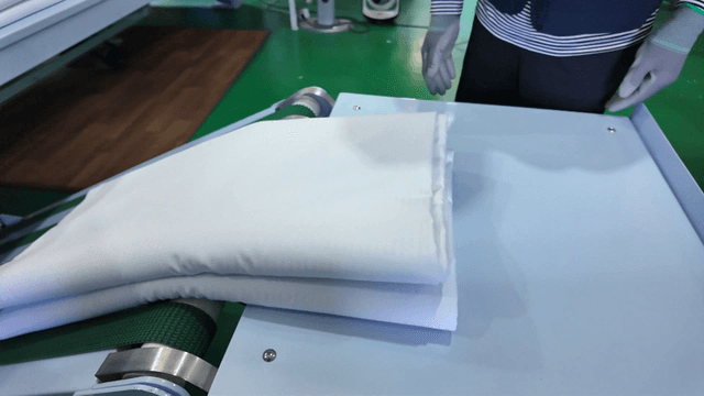 Clean white sheets processed in laundry factory