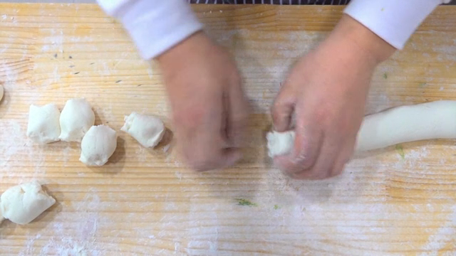 Hands shaping dough on a floured board