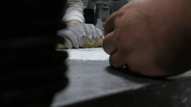 Hands kneading dough on a floured surface