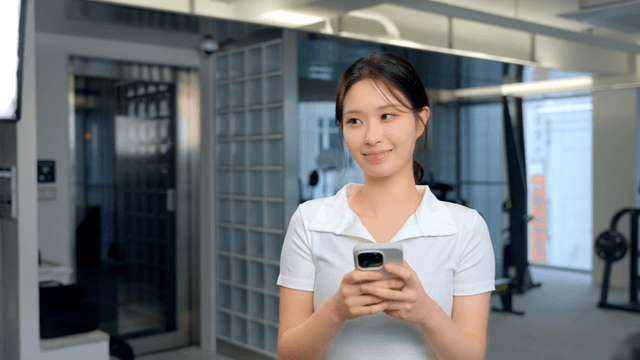 Woman smiling while holding a smartphone in a gym