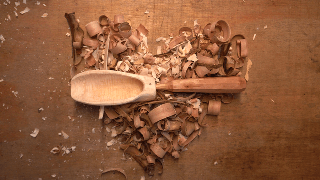 Wooden spoon surrounded by wood pieces on workbench
