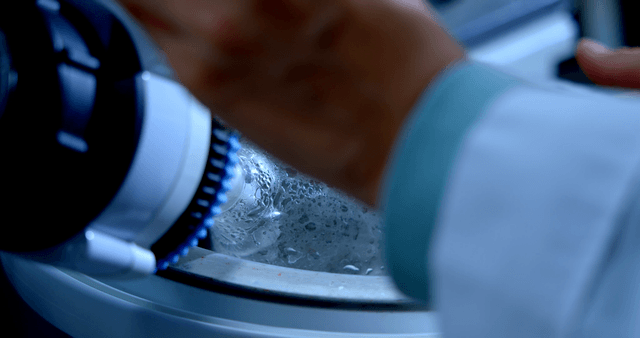 Scientist operating a machine that rotates a flask of liquid