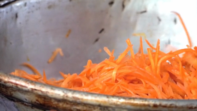 Carrots being stir-fried in a large pan