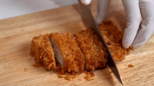 Cutting a crispy fried cutlet on a board