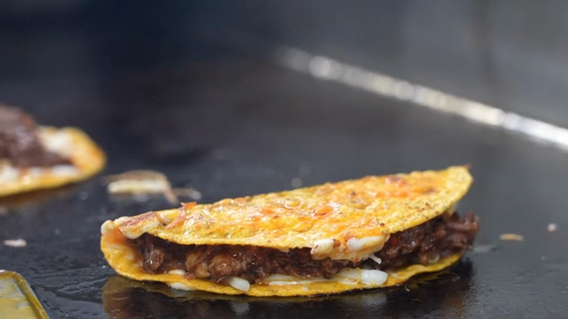 A taco being cooked on a hot griddle