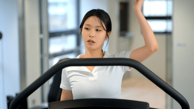 Woman stretching on a treadmill at gym