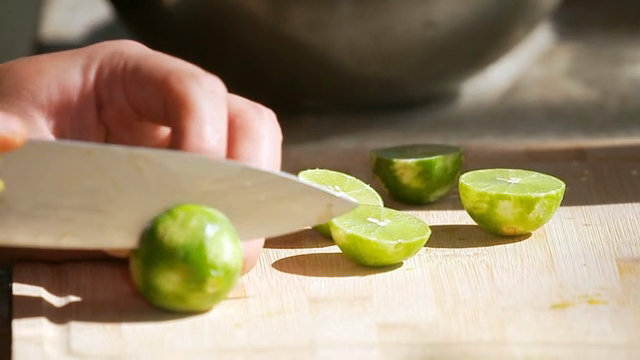 Slicing fresh limes on a wooden board