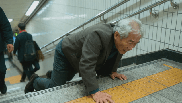 Old man struggling to climb after falling on subway stairs
