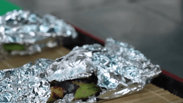Hands preparing grilled vegetables wrapped in foil