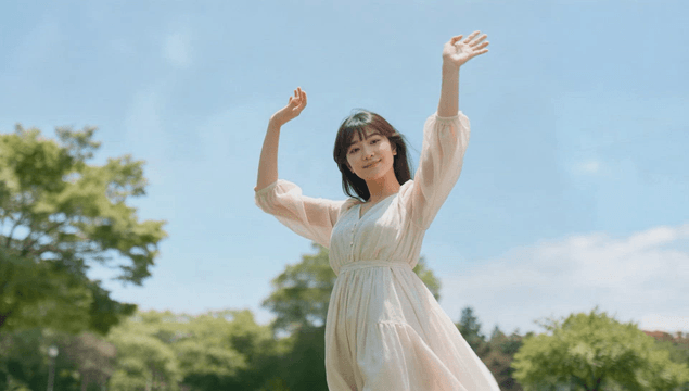 Young woman enjoying sunlight and breeze in park