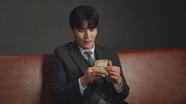 Man in a suit counting money on a sofa