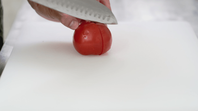 Slicing a fresh tomato on a cutting board