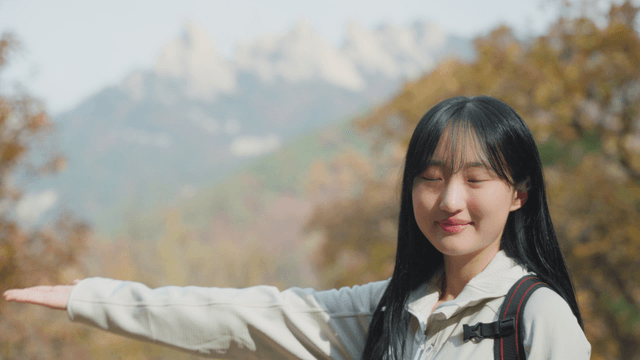 Young woman smiling at autumn scenery on high mountain