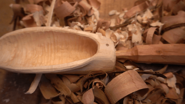 Unique wooden spoon surrounded by sawdust on workbench