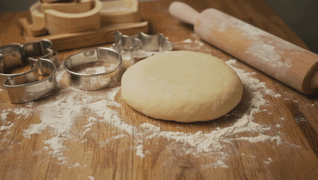 Dough and cookie cutters on a floured table